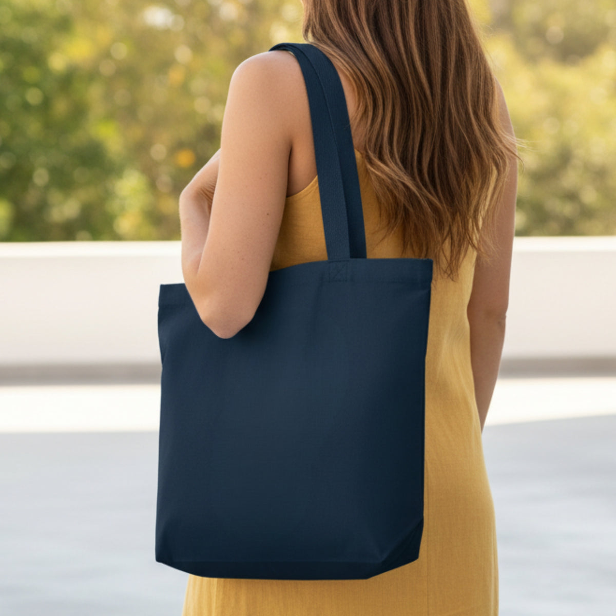 Navy canvas tote bag on shoulder, open top with wide handles.